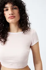 Top corto de punto acanalado color rosa, con silueta ajustada, escote redondo y ribetes blancos en cuello y mangas.