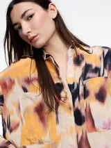 Camisa de manga larga confeccionada en viscosa crinkled con estampa de manchas. De silueta amplia y fluida, con bolsillos frontales grandes, tajos laterales y largo extendido en la espalda.