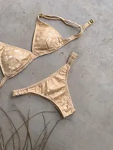 Conjunto de bikini blanco con textura, compuesto por un corpiño de triángulo fijo con breteles regulables y almohadillas desmontables, y una bombacha vedetina con frunce elástico en los costados.