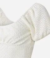 Blusa cropped color blanco, de encaje con escote en U y mangas cortas abullonadas.
