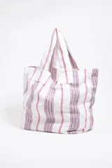 Bolso tipo shopper de lona color crudo con rayas verticales amarillas y grises. Tiene doble asa de hombro y logo de la marca estampado en el frente.