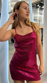 Vestido corto fucsia con lentejuelas, espalda descubierta y tirantes finos.
