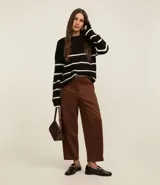 Suéter de punto pesado color negro con rayas horizontales blancas, cuello redondo y mangas largas con sisas desplazadas.