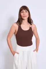Top tipo musculosa ajustado al cuerpo, color marrón oscuro, con escote redondo y tirantes finos. Un tirante presenta un detalle de argolla metálica dorada.