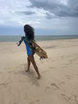 Traje de baño enterizo de lycra reciclada con estampado de hojas y flores en tonos azul, verde y rosa. Tiene mangas largas, cierre en la espalda y protección SPF 50.