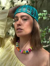 Collar corto con cuentas de resina y cerámica de colores naranja, rosa, verde, celeste y beige. Tiene tiento sintético con cierre ajustable.