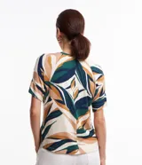 Blusa de viscosa con estampado de hojas en tonos verde, azul y ocre. Tiene cuello redondo y mangas cortas.