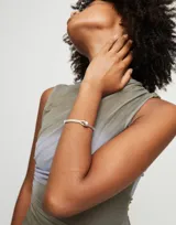 Pulsera semirígida de aleación de metales bañada en plata con cuero color marfil y una esfera plateada.