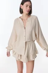 Camisa beige de manga larga con botones y detalles de encaje.