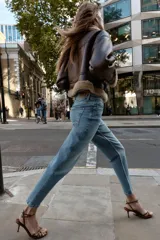 Pantalón de jean azul de tiro alto, corte mom fit, tobillero y con cinco bolsillos. Cierre frontal con cremallera y botón.