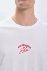 Remera blanca de manga corta con cuello redondo y estampado rojo en el pecho con la leyenda "Hunting the waves" y un diseño de surfistas.
