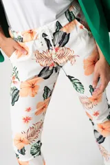 Pantalón babucha blanco con estampado de flores y hojas en tonos naranja, marrón y verde.