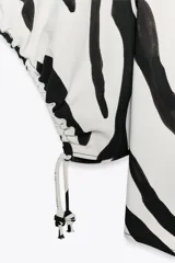 Top de cuello redondo y escote pico con estampado animal print cebra en blanco y negro. Manga corta abullonada ajustable con lazadas.