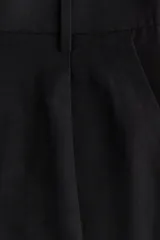 Short negro de tiro alto con pinzas delanteras, bolsillos laterales y trabillas para cinturón.