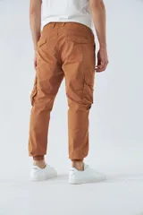 Pantalón cargo color marrón con corte slim, elástico en cintura y cordón ajustable, bolsillos cargo con botones y puños elásticos. Confeccionado en algodón y spandex.