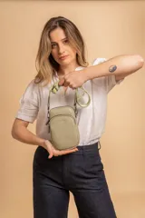 Bandolera pequeña tipo 'phone bag' de símil cuero color rosado pálido, con cierre de cremallera y correa ancha de tela con diseño de chevron en tonos claros.