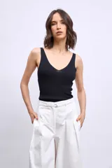 Pantalón de denim color crudo, corte ancho y tiro alto, con grandes calados florales bordados en contraste a lo largo de ambas piernas.