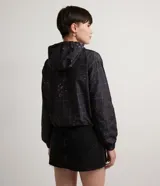 Campera cropped con capucha, de poliéster color negro con estampado de cuadros y salpicaduras de colores. Tiene cordón de ajuste en la capucha, elástico en puños y ruedo, bolsillos con cremallera y cierre frontal con cremallera.
