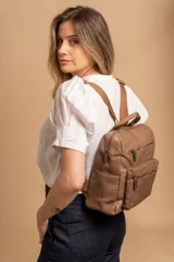 Mochila mediana de símil cuero color beige, con asa superior, dos compartimentos principales con cierre y dos bolsillos frontales con cierre. Las correas son ajustables y de color beige.