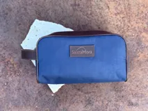 Neceser de lona verde con detalles en cuero color beige y etiqueta con logo de la marca Sierra Mora.
