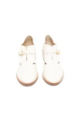 Zapato de cuero color blanco con textura reptil en el talón, corte lateral y hebilla dorada.