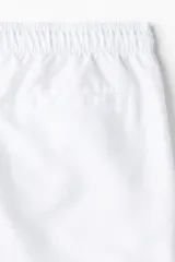 Short de baño blanco de tela con tajos laterales cortos. Elástico revestido con cordón para ajustar en la cintura, bolsillos laterales y bolsillo atrás con cierre autoadherente. Suspensor interior de malla.