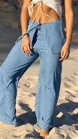 Pantalón de jean celeste con corte amplio y sobrefalda cruzada con lazo.