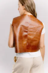 Chaleco de cuero color marrón con estampado brillante, de corte recto y largo a la cintura. Su diseño abierto en el frente lo convierte en una prenda versátil, fácil de combinar tanto con básicos como con looks más elaborados.