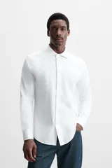 Camisa blanca de algodón, corte regular, con cuello italiano abierto, manga larga con puños abotonados y cierre frontal con botones.