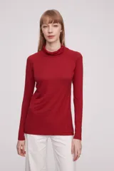 Polera roja de manga larga, con cuello drapeado y ajuste al cuerpo.