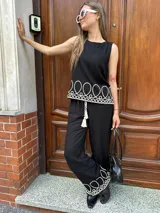 Blusa negra sin mangas con bordado blanco en el ruedo.