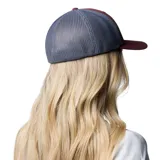 Gorro Columbia color ladrillo con paneles traseros de malla gris y parche frontal con logo de la marca y diseño de montaña y atardecer.