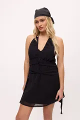 Minivestido negro con escote halter, espalda descubierta, cintura drapeada y falda con transparencias.