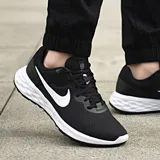 Championes de running Nike Revolution 6 NN, color negro con logo azul y suela blanca.