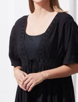 Kaftan blanco largo con mangas cortas y abertura central. Presenta apliques de puntilla en el escote, cintura y ruedo. Se ata en la cintura con un lazo.