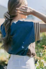 Blusa marrón con cuello en V, mangas cortas con detalle de tela rayada en los puños y corte holgado.