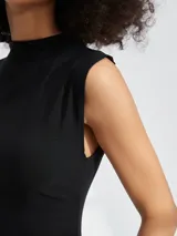 Vestido corto negro, ajustado al cuerpo, sin mangas y con cuello redondo alto.