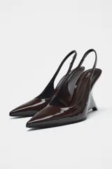Zapato de tacón tipo cuña destalonado en charol color marrón chocolate. Tacón con forma asimétrica. Tira trasera con pieza elástica. Acabado en punta.