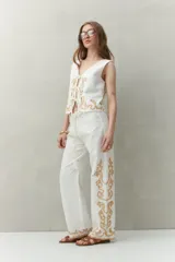 Pantalón blanco de algodón con bordado artesanal a contratono en los laterales y ruedo, de corte recto y caída fluida.