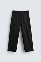 Pantalón negro de corte amplio confeccionado en tejido técnico, con cintura elástica, bolsillos delanteros y trasero de parche. Presenta bandas laterales a tono.