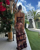 Vestido largo de corte ajustado, con estampado abstracto en tonos rosados y marrones. Presenta un escote pronunciado con detalle de volados en color púrpura, abertura en el abdomen y tajo lateral.
