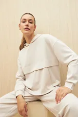 Canguro color beige de la línea Essence, con capucha, corte amplio y detalle de recorte frontal.