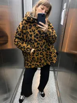 Campera con capucha de tela tipo peluche color marrón con estampado animal print de leopardo en negro.