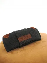 Estuche para lentes color borgoña con textura símil cocodrilo y cierre con broche a presión.