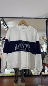 Buzo blanco con mangas azul marino y franja horizontal azul marino con la inscripción "1996 HAMPTONS NEW YORK".