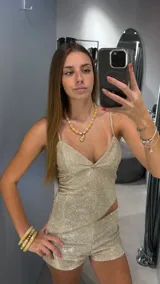 Conjunto de top y shorts dorados con brillos. El top es ajustado, con breteles finos y escote en V. Los shorts son cortos y ajustados.