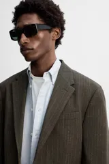 Blazer straight fit color marrón oscuro con finas rayas verticales claras. Confeccionado en tejido con lana de origen italiano. Cuello con solapas de muesca y manga larga acabada en puño con botones. Bolsillos de vivo en pecho y de solapa en cadera. Detalle de bolsillo interior. Bajo con aberturas en espalda. Cierre frontal de botonadura.