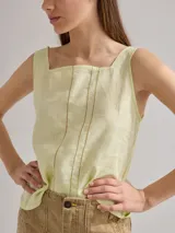 Musculosa color verde claro de lino en el frente y algodón en la espalda, con breteles anchos y escote cuadrado. Presenta detalle de pequeñas perforaciones verticales en el frente.