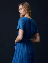 Vestido Luxology de tencel color azul, con escote en V cruzado, cintura elastizada con lazo, manga corta con volados y falda midi con volados.