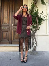 Falda corta tejida color gris con detalles dorados, con flecos largos en el ruedo.